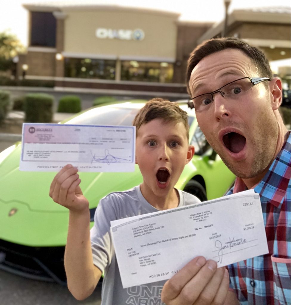 Cody Sperber and Hudson Sperber in front of Chase Bank holding up a real estate profit check.